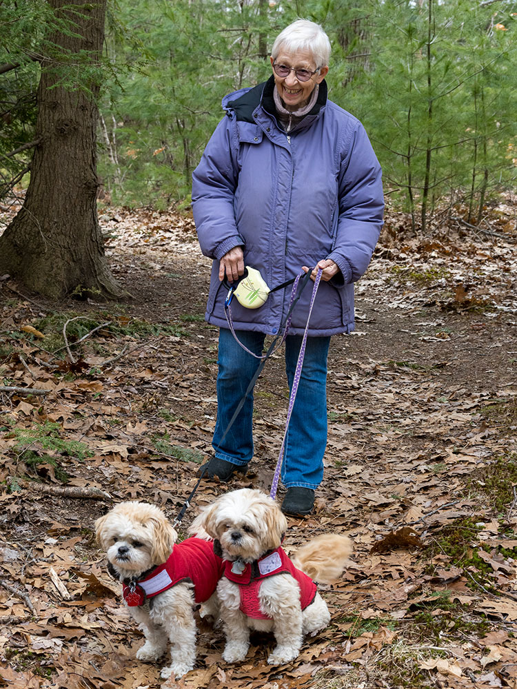 Thornton Oaks' resident, Dee, walking her dogs on the trails